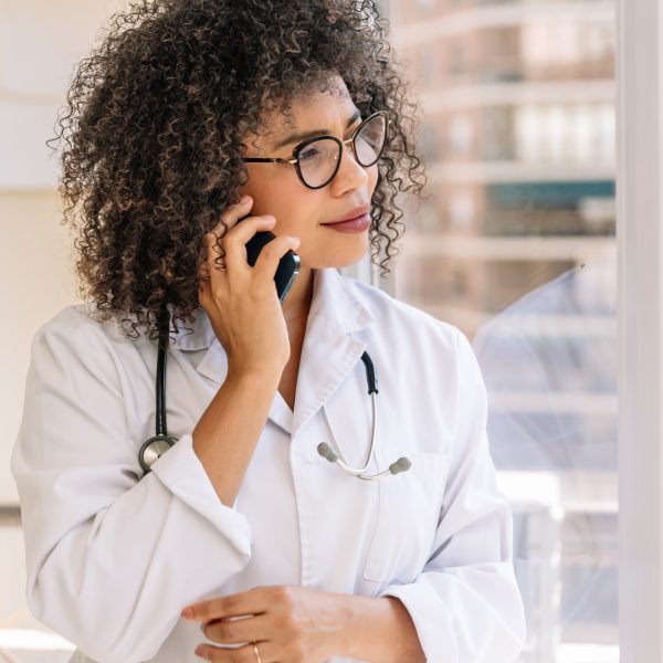 African american female doctor in lab coat and stethoscope talking on mobile phone African american female doctor in lab coat and stethoscope talking on mobile phone
